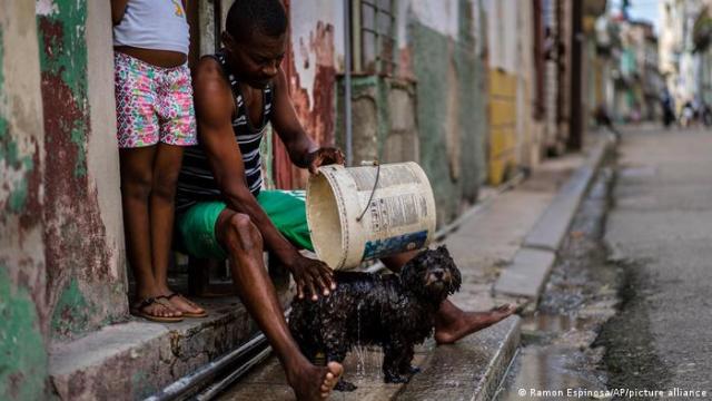 Un vecino enjuaga a su perro en una barriada humilde La Habana.